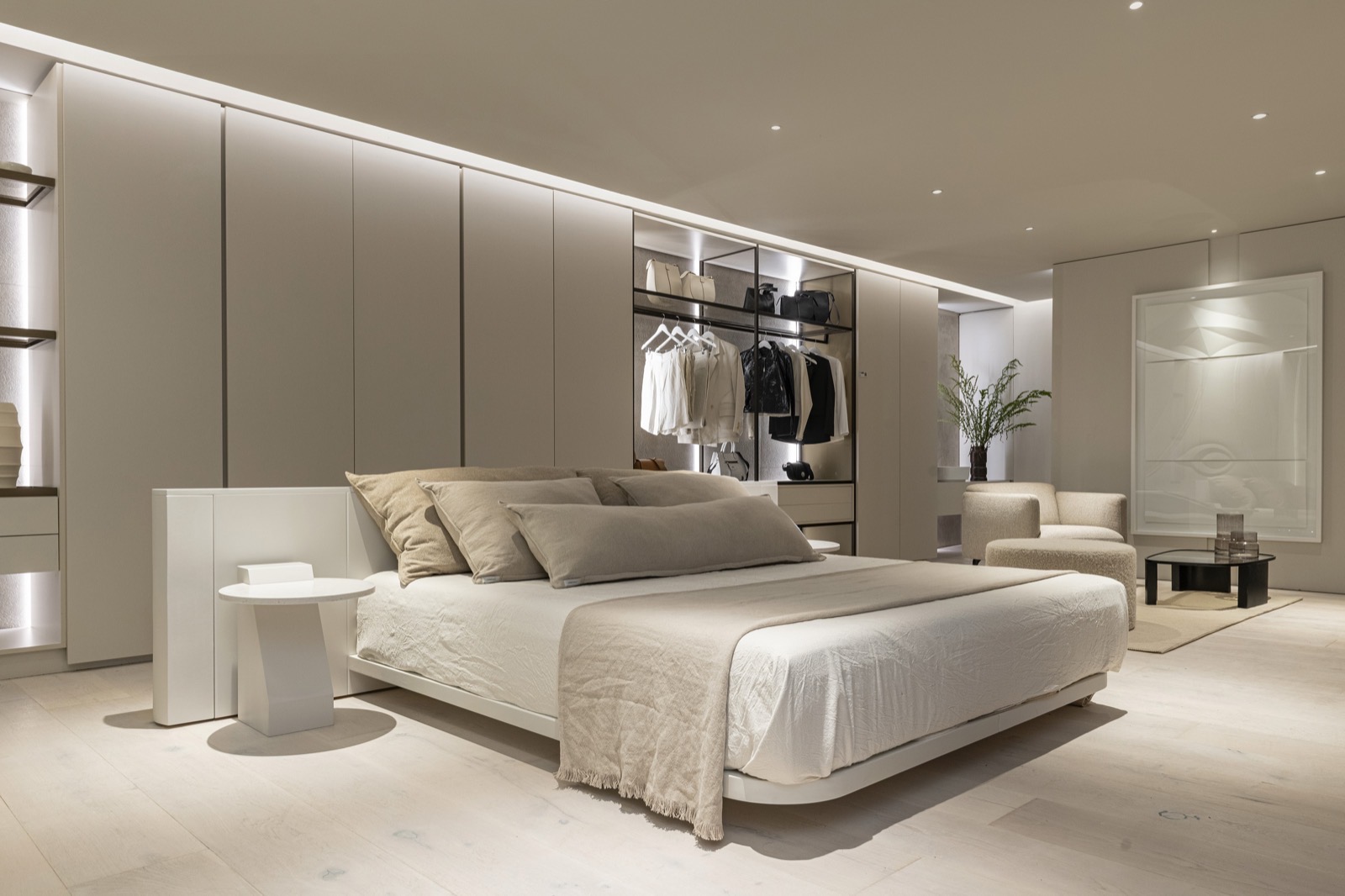 Dormitorio con cama baja, frentes laqueados y vestidor vidriado con iluminación integrada